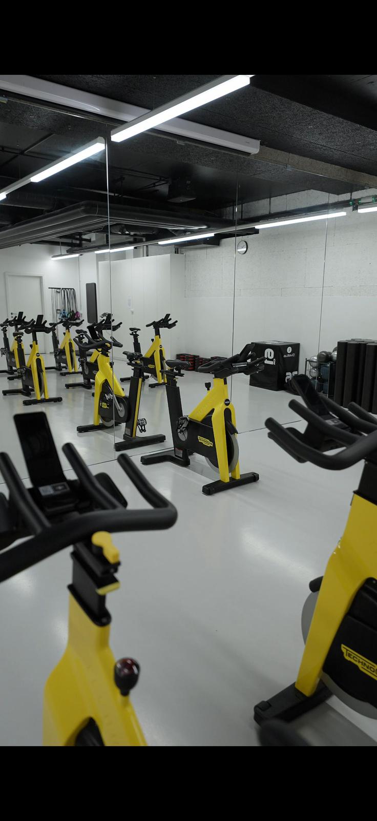 Vue rapproch&eacute;e de v&eacute;los de spinning jaunes et noirs dans une salle miroir
