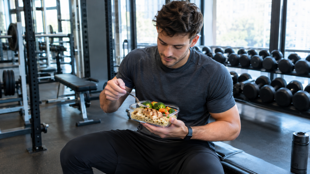 Homme mangeant un repas sain de poulet et l&eacute;gumes assis sur un banc de musculation